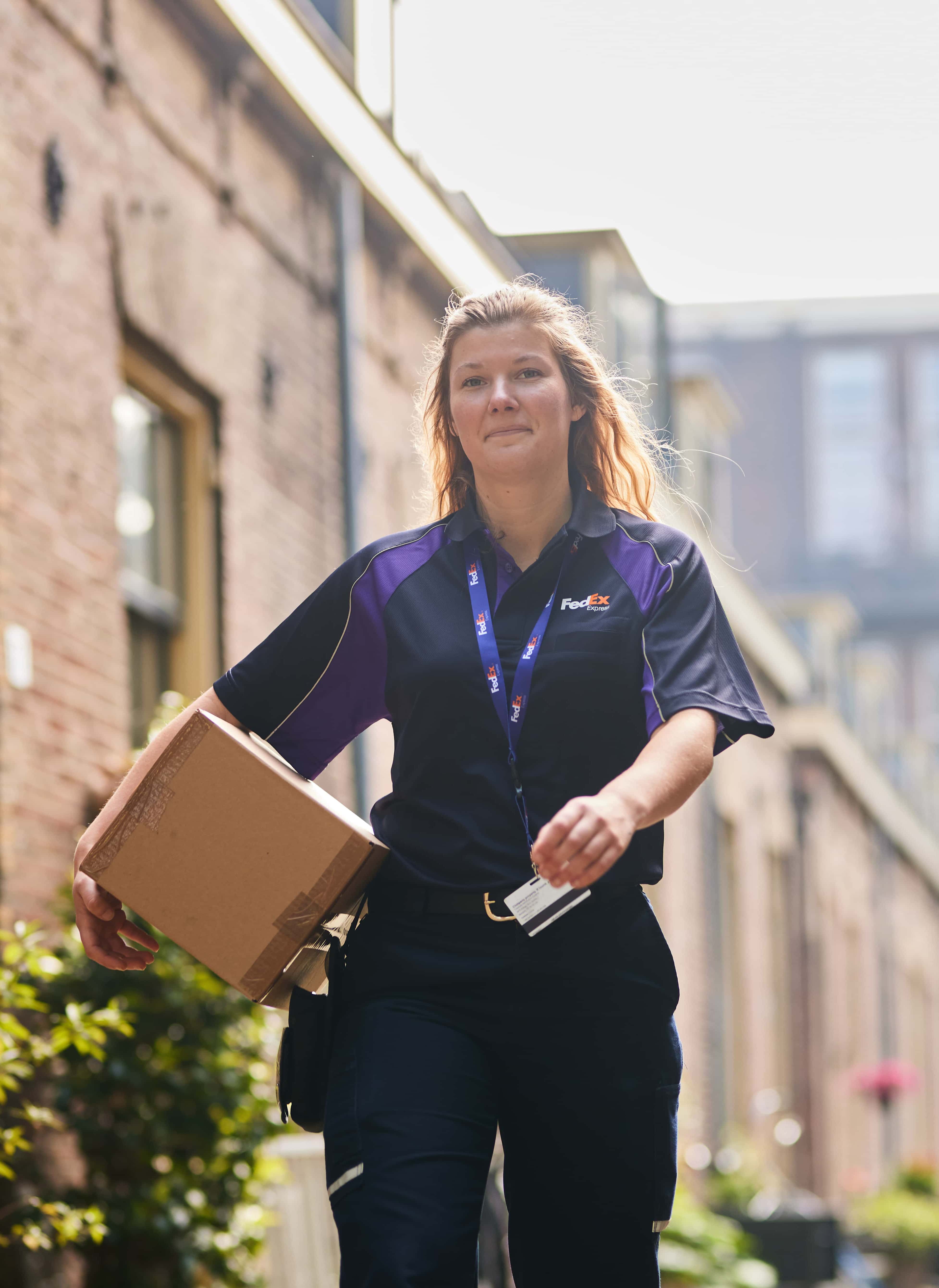 FedEx employee smiling and delivering a pacakge